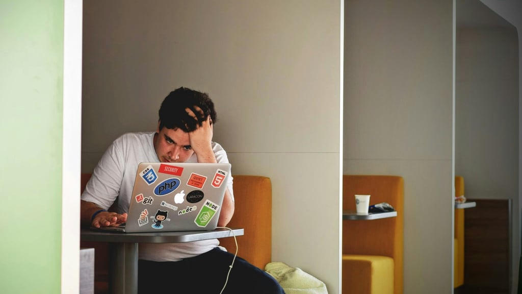 Stressed individual using a laptop at a table, symbolizing challenges in remote learning amid global