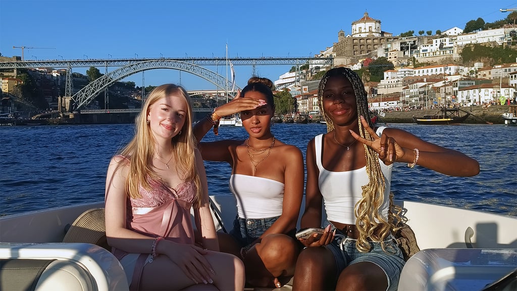 Three girls posing for a photo on the Endure speedboat with Dom Luís I Bridge in the background