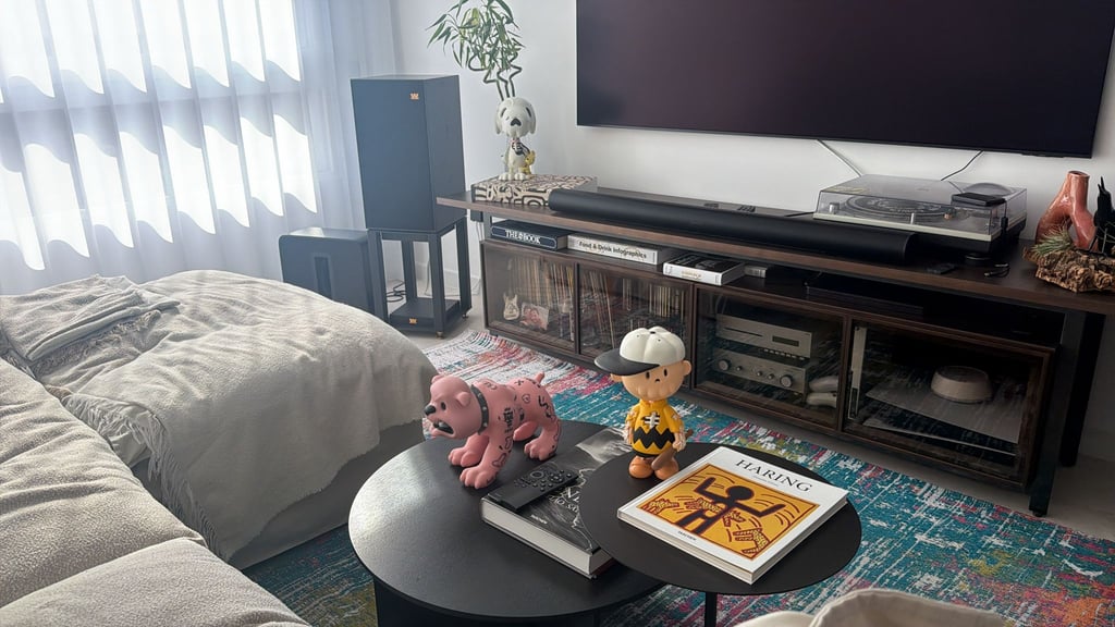 Modern living room featuring a home theater setup, record player, and designer art toy collectibles.