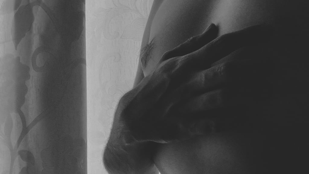 Mano sobre el pecho en primer plano con luz suave lateral.