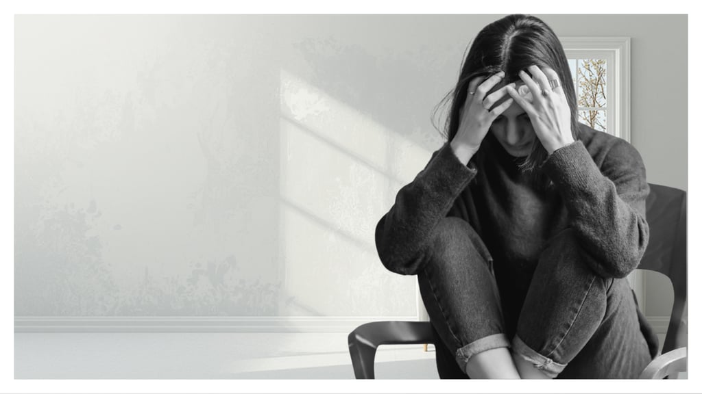 A stressed woman sits in a chair holding her head, illustrating anxiety, depression, and mental health struggles.