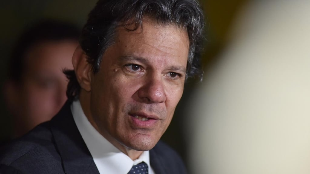 Fernando Haddad em close, com uma expressão séria e usando um terno.