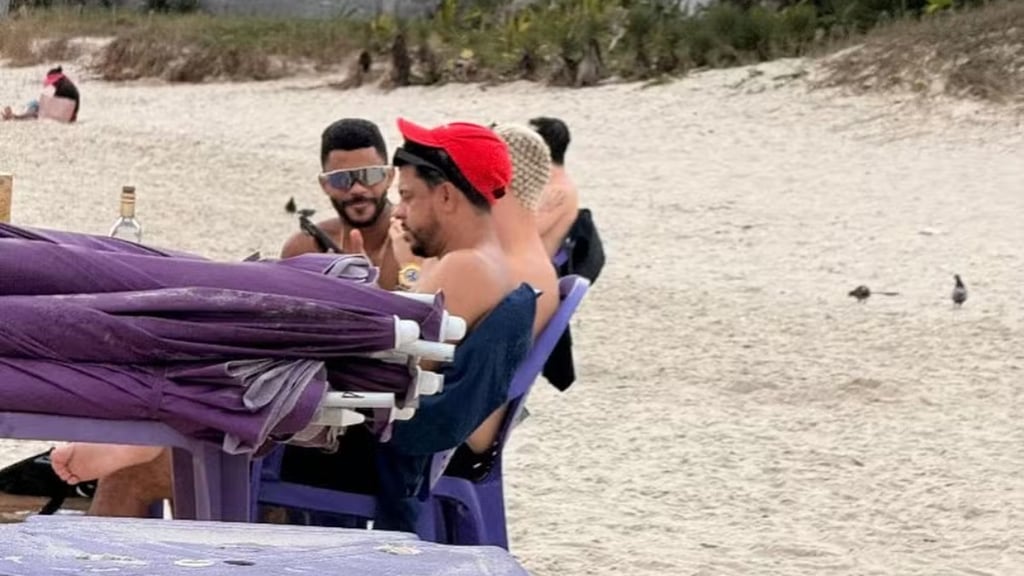 a man in a red hat and sunglasses on a beach