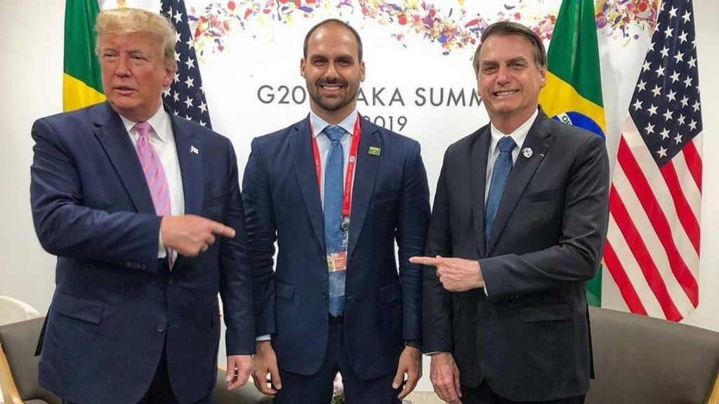  Donald Trump e Jair Bolsonaro apontando para Eduardo Bolsonaro em uma cúpula do G20.