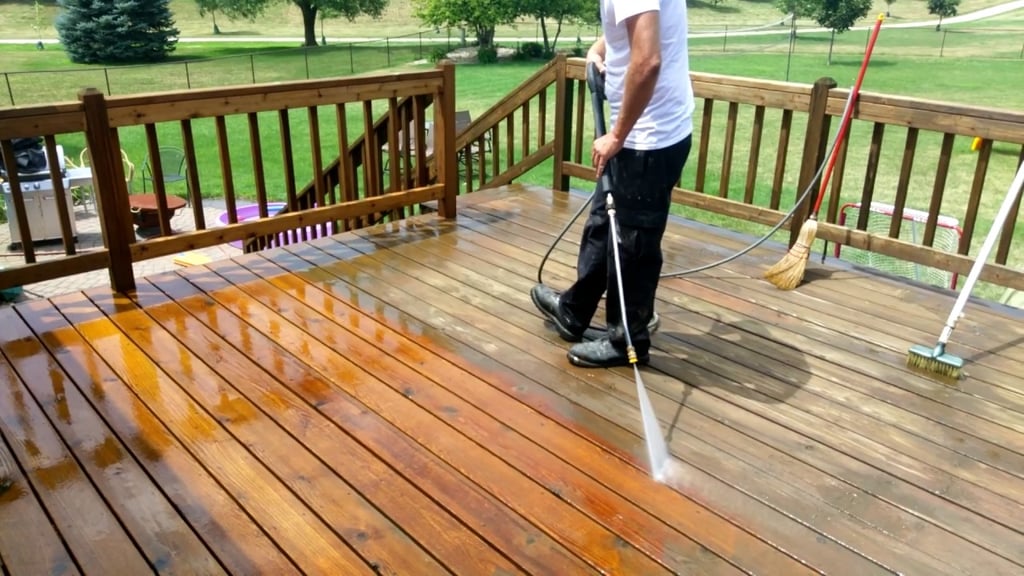 A man cleaning a wooden deck with a pressure washer