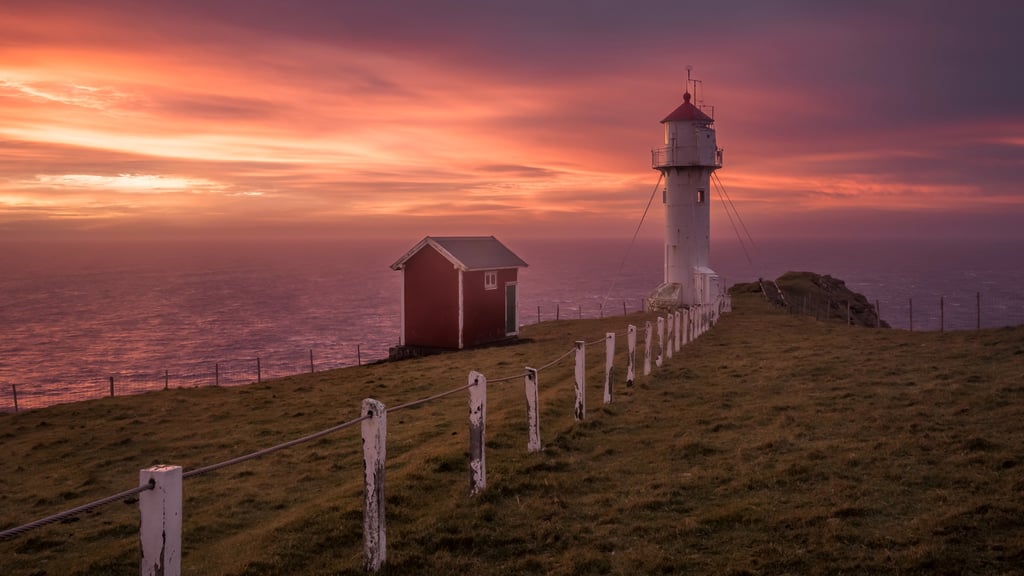 Sunrise at Akrabyrgi lighthouse with soft golden light, rugged cliffs and Atlantic Ocean, Faroe Islands landscape photography