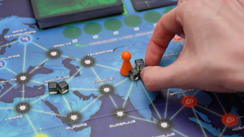 Ranka nuima ligų kubelius nuo stalo žaidimo lentos