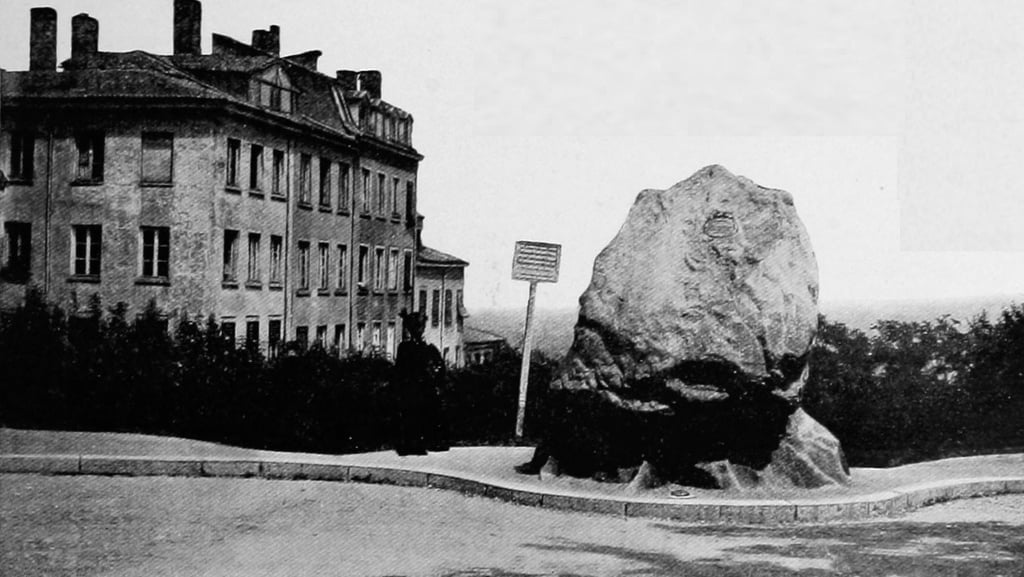 Vintage black and white photo of a large commemorative boulder monument in a European city plaza.