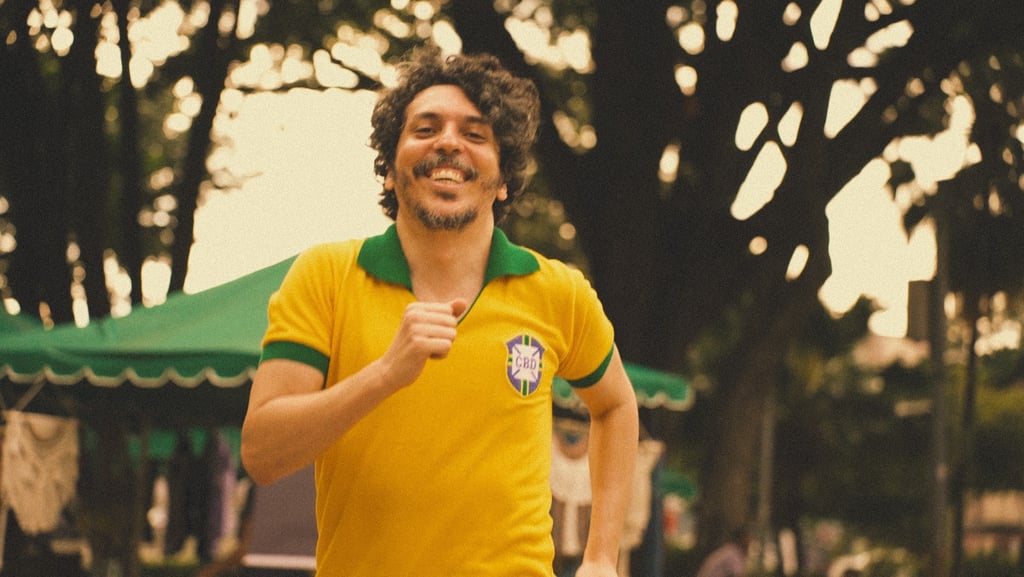 Smiling man running outdoors wearing a vintage yellow and green Brazil soccer jersey.