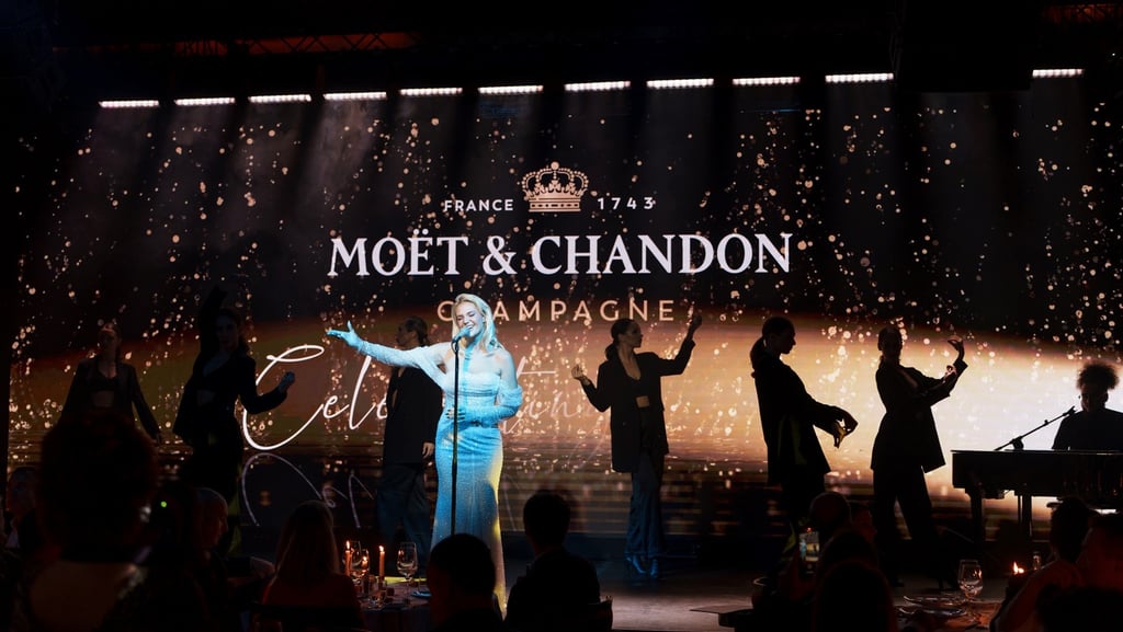 Singer performing at a Moët & Chandon champagne luxury event with dancers on a stage.