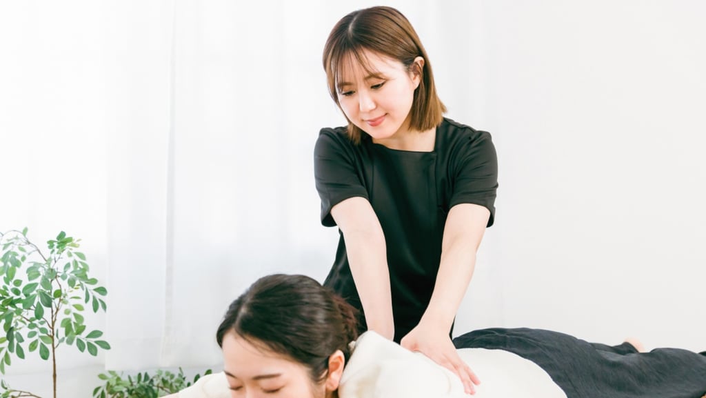 女性セラピストがベッドで横になる利用者に全身もみほぐしを行っている様子｜堺市のニュースならサカイタイムズ