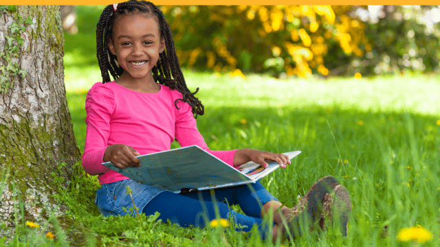 A little girl reading at the park