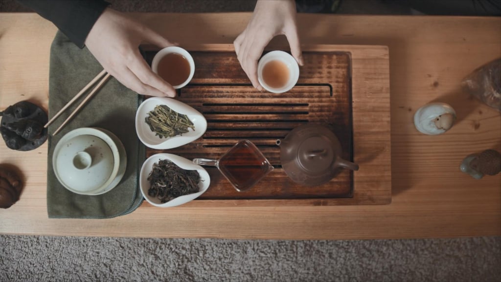 Tea set on the table with two people drinking tea