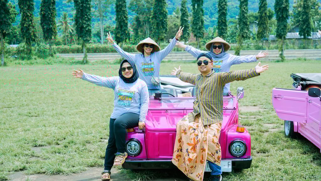 Wisatawan menikmati perjalanan VW Safari melewati pedesaan hijau dengan latar lapangan 