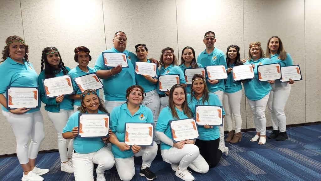 A group of professionals in blue shirts holding achievement certificates at a corporate ceremony.