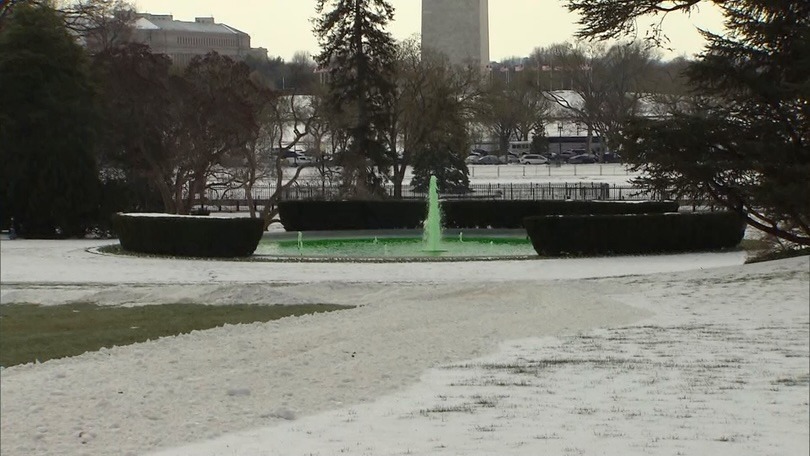 fountain with green water for Saint Patrick's Day in a snowy landscape.
