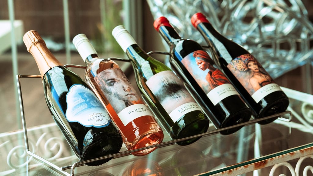 A rack of five Bloupunt wines on a glass table displaying Martin and Samantha Osner's art labels