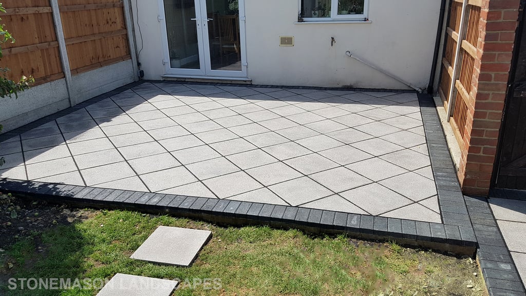 Basic grey patio with black charcoal edging blocks slabs laid in diamond format