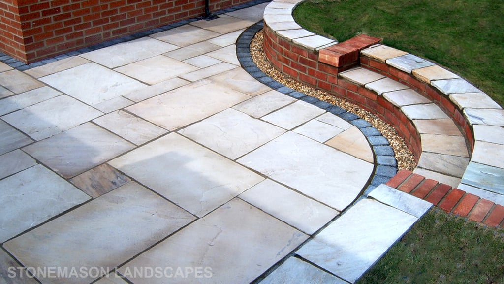 Multi-level sunken sandstone patio step up to lawn with retaining wall