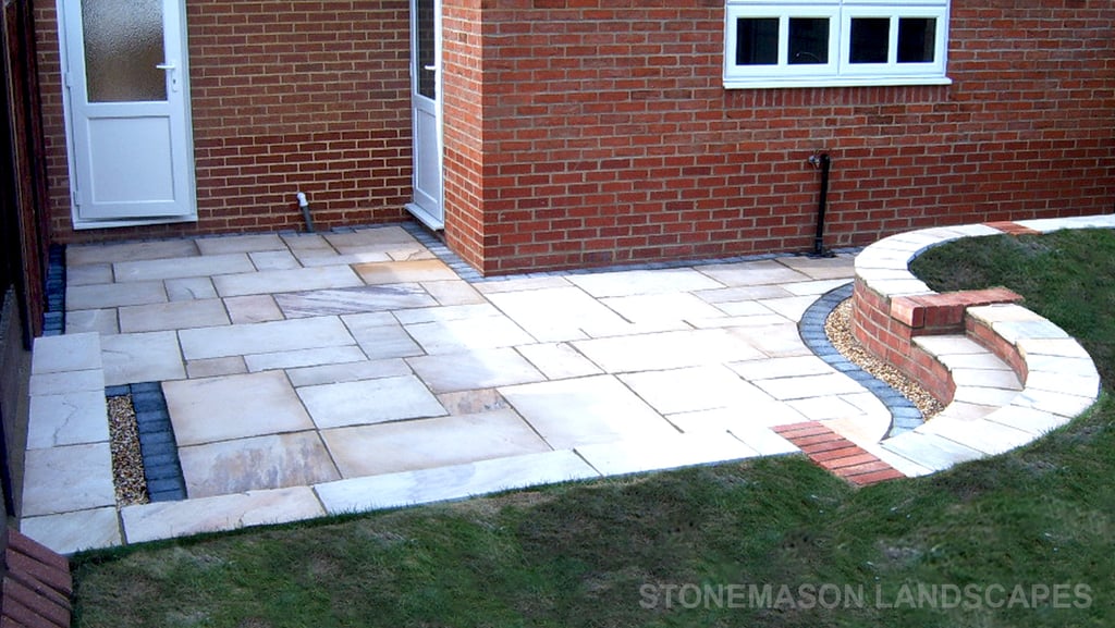 Multi-level sunken sandstone patio step up to lawn with retaining wall