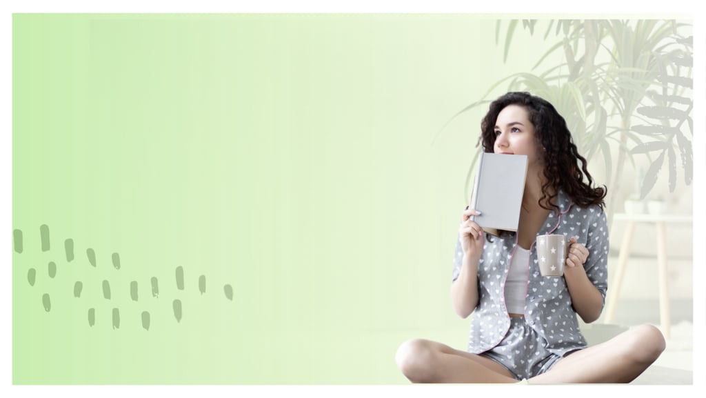 Young woman in pajamas holding a book and coffee mug in a relaxing green room.
