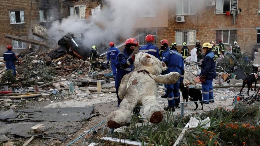 a teddy bear is sitting on the ground next to a fire hydrant