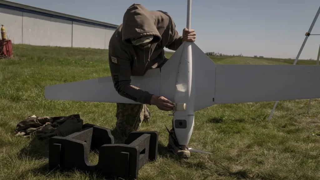 a man in a hoodie is holding a remote control plane