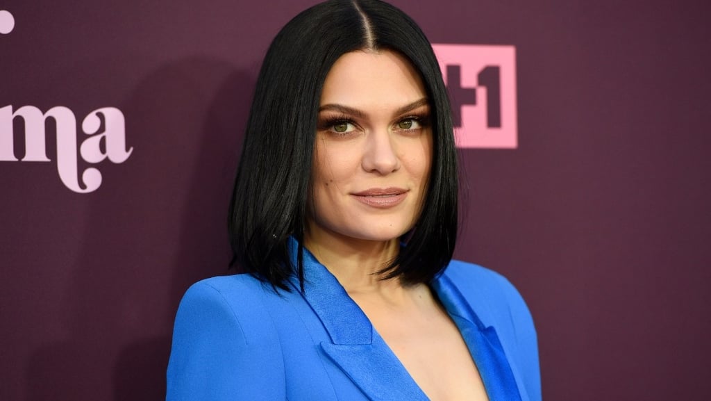 Jessie J com cabelo curto e preto, posando com um blazer azul.