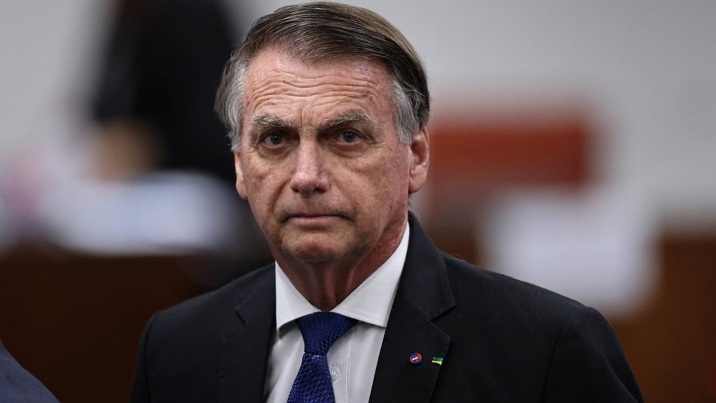 Close de Jair Bolsonaro, com uma expressão séria, olhando para a câmera.