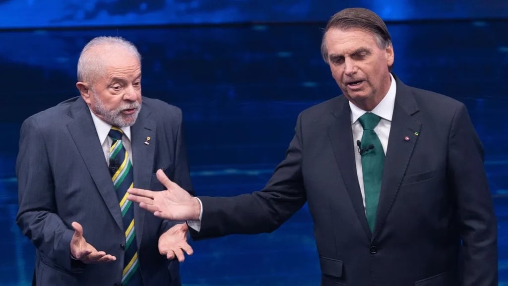 Lula e Jair Bolsonaro debatem em um palco, gesticulando um para o outro.
