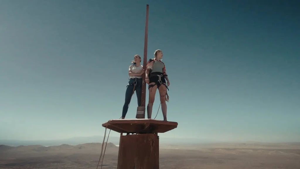 two people standing on top of a pole with a pole