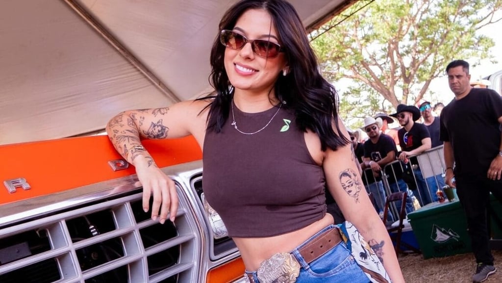 Ana Castela sorrindo apoiada em um carro