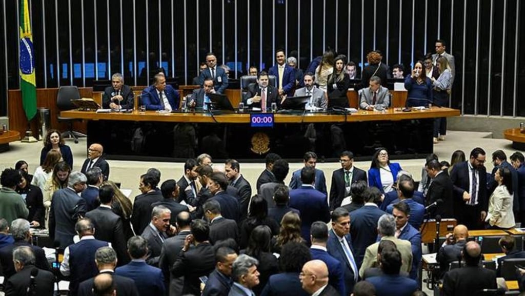 Deputados e senadores em um plenário, alguns de pé e outros sentados.
