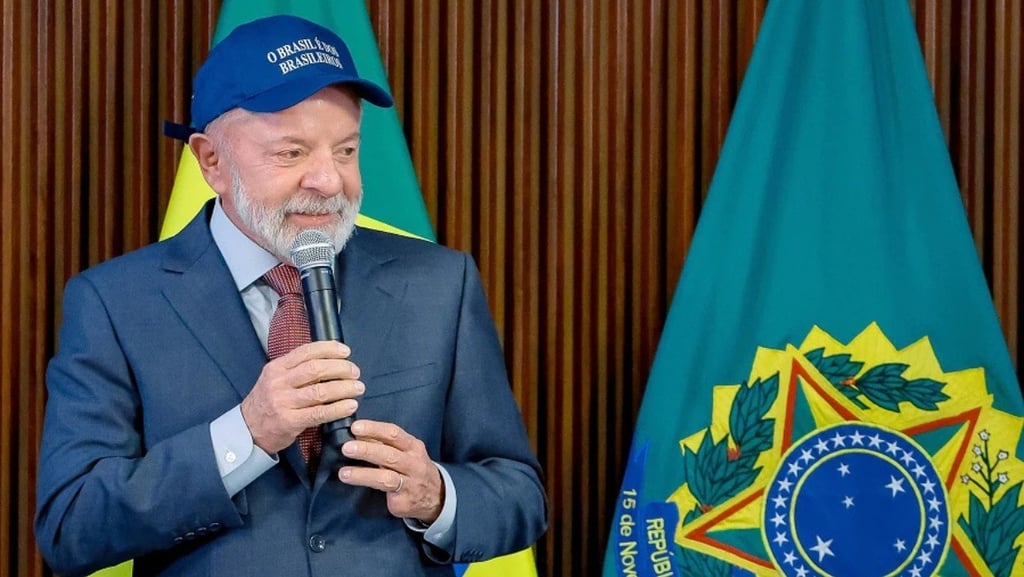 Lula, com um boné azul e um microfone na mão, em um discurso.