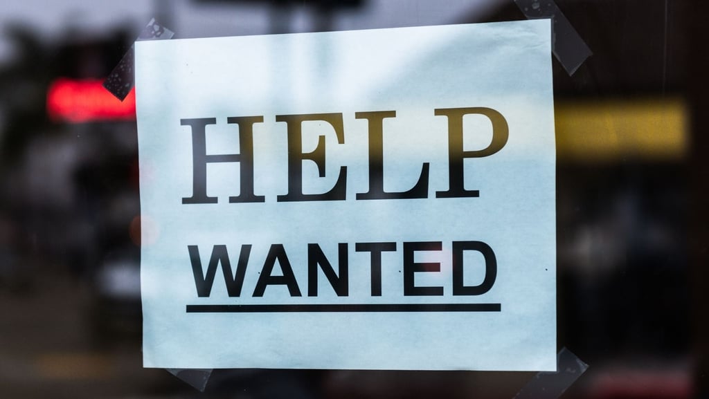 A "Help Wanted" sign taped to a store window
