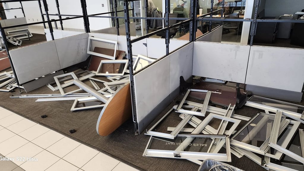 Dismantled office cubicles and metal workstation frames scattered across an office floor during a renovation.
