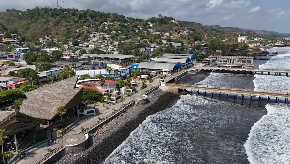 Aerial view of La Libertad pier and beach in El Salvador featuring the scenic coastal boardwalk and ocean waves.