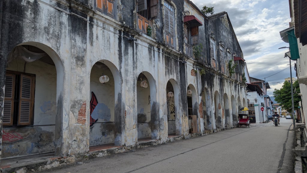Historic colonial buildings with arched walkways on a street in George Town, Penang.