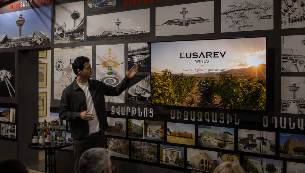 A man presenting Lusarev Wines on a screen surrounded by architectural sketches and vineyard photos.
