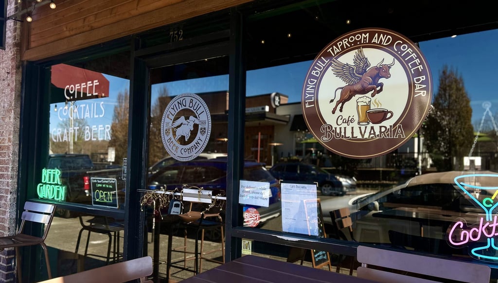 Storefront of Flying Bull Taproom and Coffee Bar with cafe seating and neon signs for craft beer and cocktails.