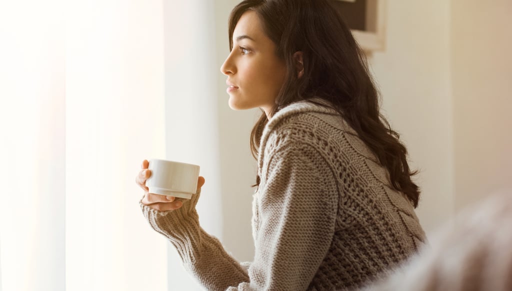 Woman holding a warm drink while taking a quiet moment to relax and reset after stress