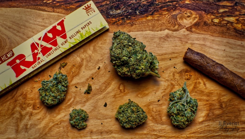 raw rolling papers with cannabis product and a cigar on wood