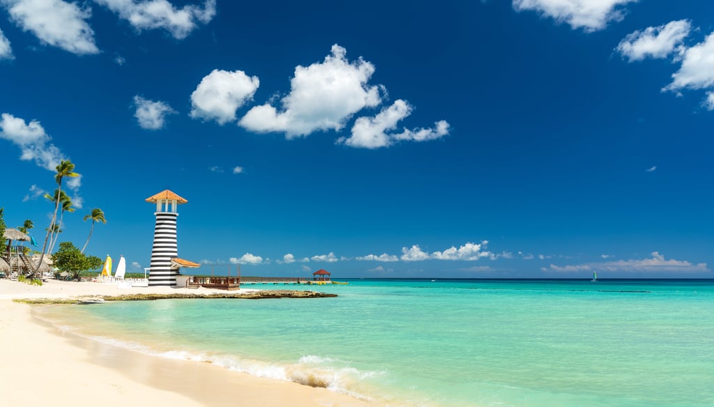 Scenic beach with turquoise water and striped lighthouse in Bayahibe, Dominican Republic
