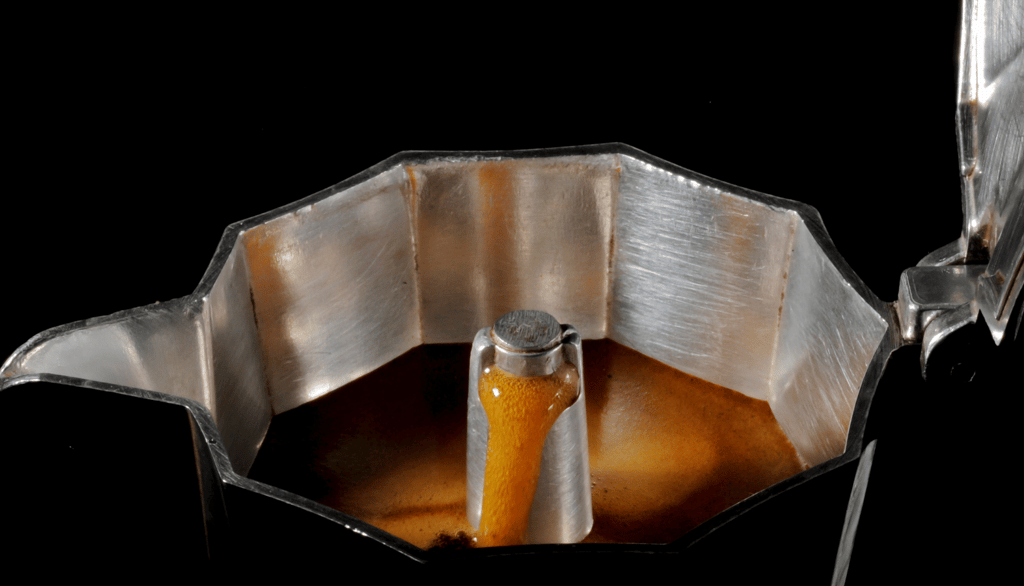 "Cafeteira italiana com a tampa aberta cheia de café fresco, ilustrando o preparo de café em Curitib