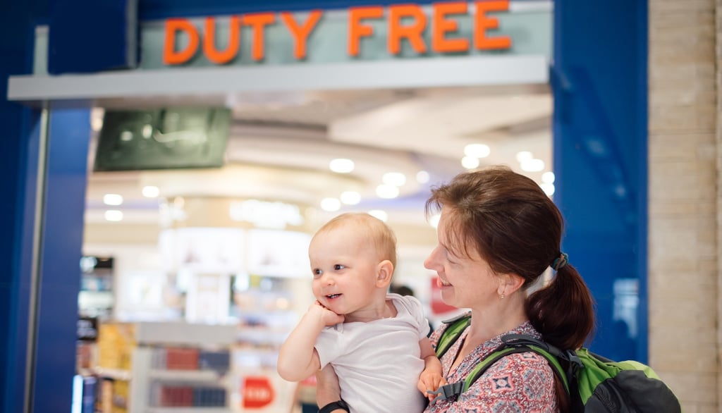 Young mother with baby in Duty Free at airport