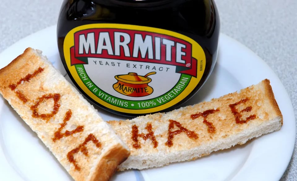 Jar of Marmite on a white plate with two soldiers that read love and hate