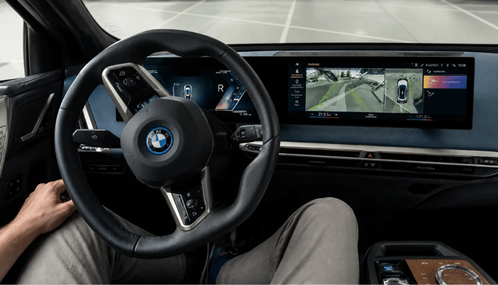 Volante virando sozinho durante estacionamento automático com sistema Park Assist ativo no painel do