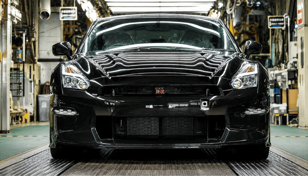 Novo Nissan GT-R preto com visual esportivo em fábrica iluminada.