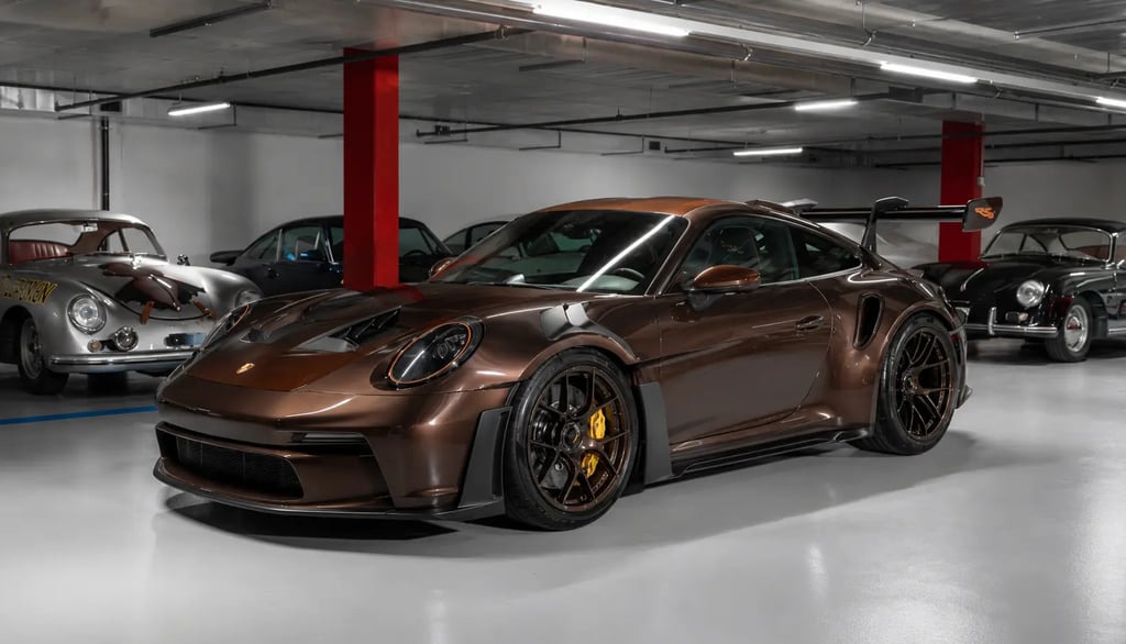 Porsche 911 GT3 RS marrom exclusivo em garagem com carros clássicos ao fundo