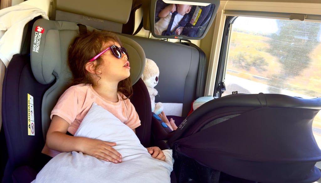 un enfant en train de dormir dans un siège auto à coté d'un bébé également dans un siège auto